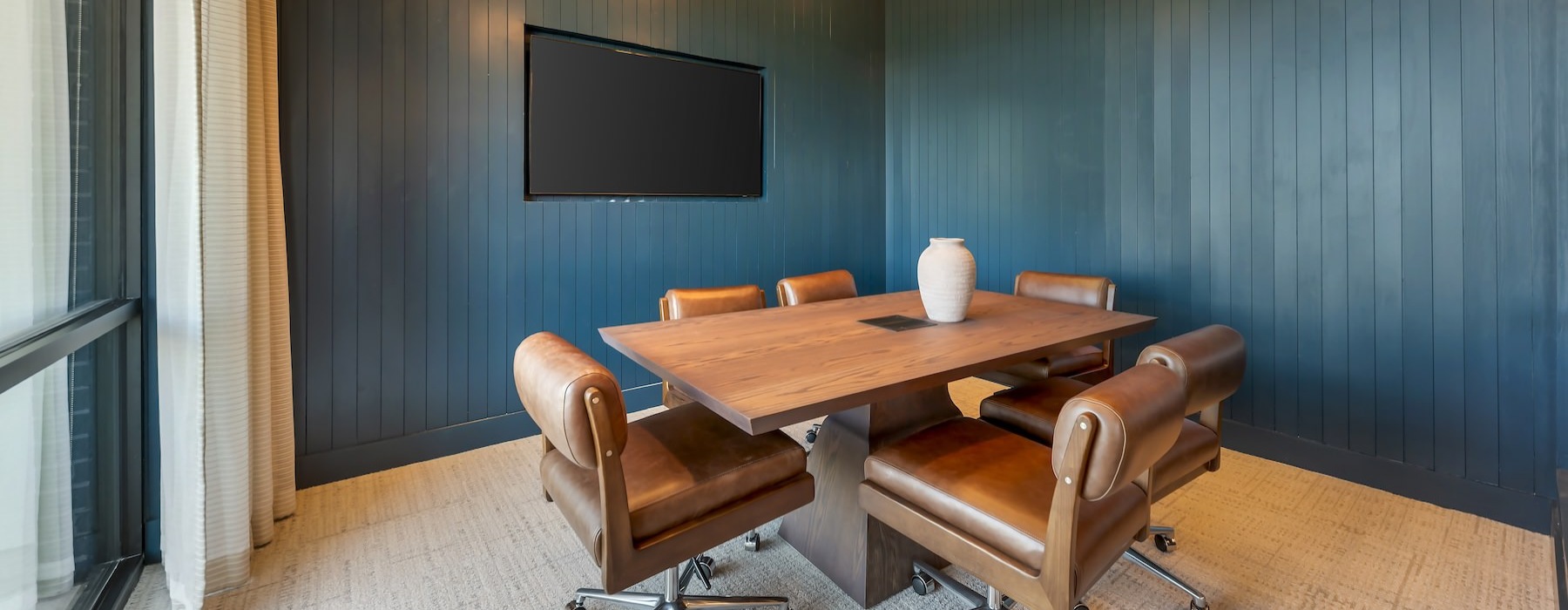 a room with a table, chairs and a tv